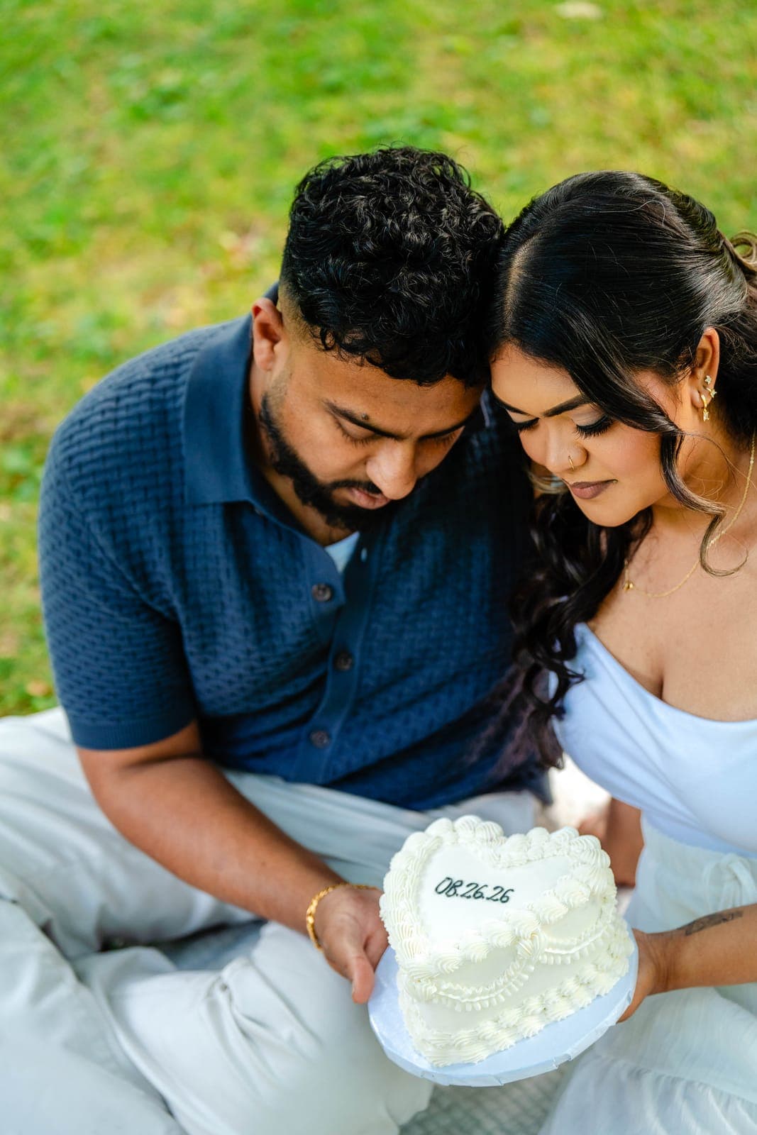 Close-up of Piratheepan and Shivanna revealing a heart-shaped cake marked with their wedding date, 08.26.26