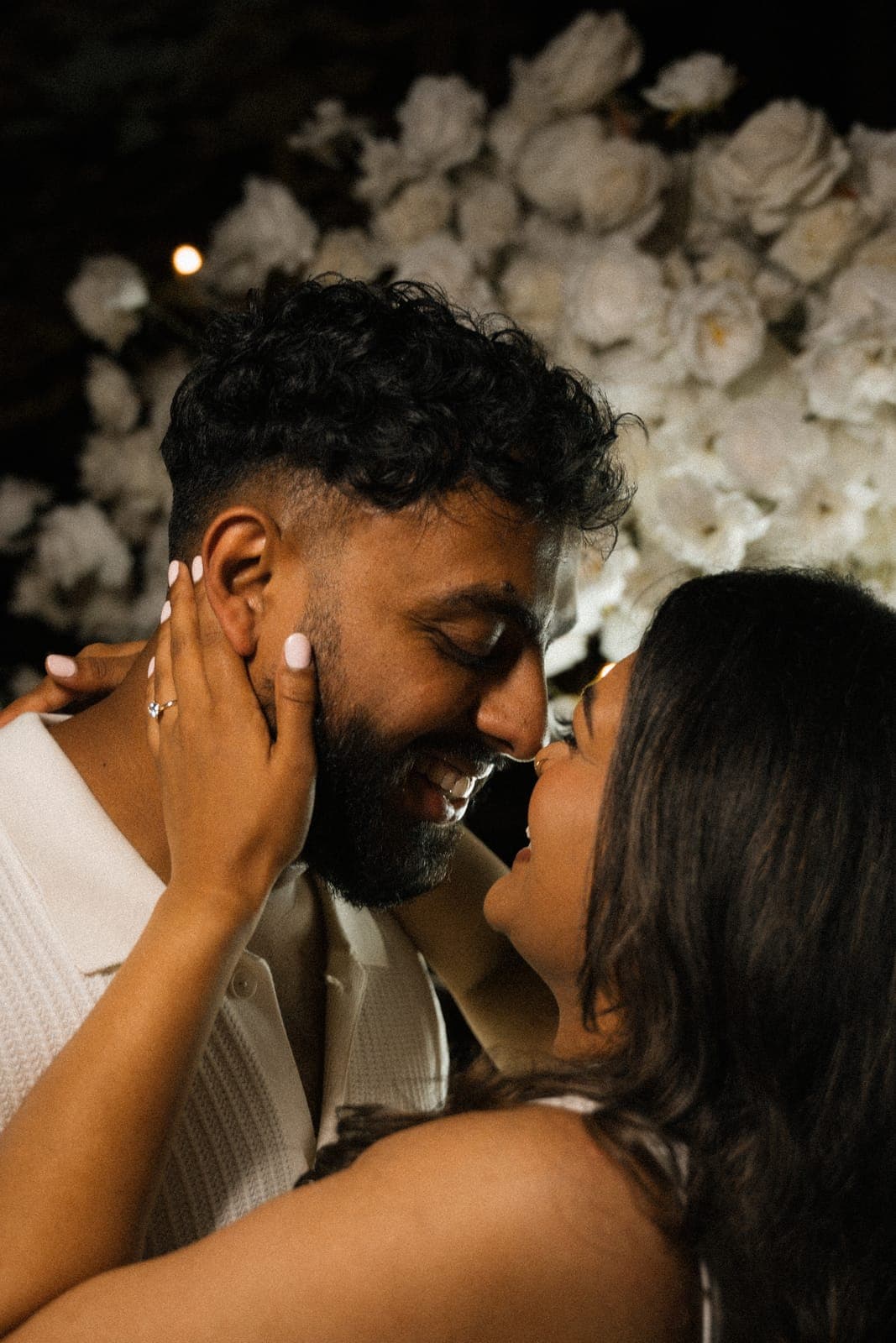 Black-and-white close-up of Piratheepan and Shivanna with foreheads touching, about to kiss, floral arch blurred behind them